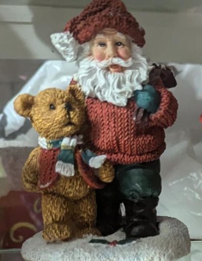 A charming figurine depicting Santa Claus joyfully holding a teddy bear, embodying the spirit of Christmas.