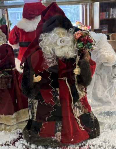 A Santa Claus figure is showcased in a glass case, highlighting his festive attire and cheerful expression.