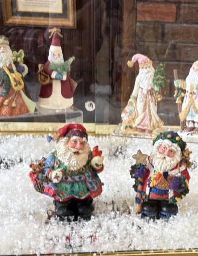 A display case featuring various Santa Claus figurines, showcasing their festive designs and cheerful expressions.