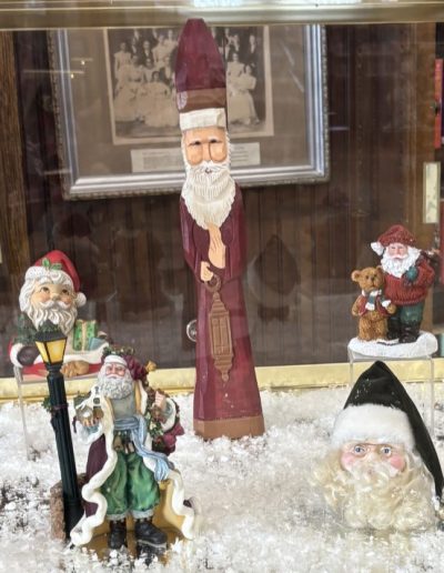 A display case featuring various Santa Claus figurines, showcasing their festive designs and cheerful expressions.