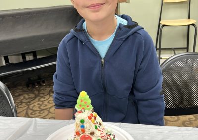 A cheerful young boy holds a plate of gingerbread, celebrating his successful gingerbread house building project.