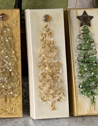 A collection of five Christmas trees crafted from wood and decorated with crushed glass and beads, embodying a rustic holiday charm.