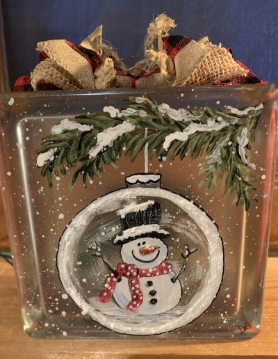 A glass block featuring a cheerful snowman, capturing the essence of winter in a decorative display.