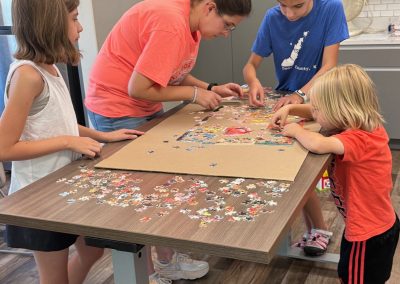 Children working on a jigsaw puzzle at a wooden table.