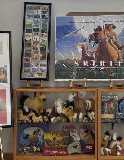 Display of "Spirit: Stallion of the Cimarron" memorabilia including posters, plush toys, and merchandise.