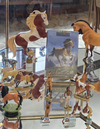 Display of "Spirit: Stallion of the Cimarron" figurines and memorabilia in a glass case.